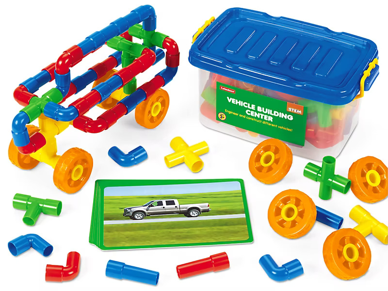 Colorful vehicle-building toy set with assorted tube pieces and wheels beside a blue storage box. 
